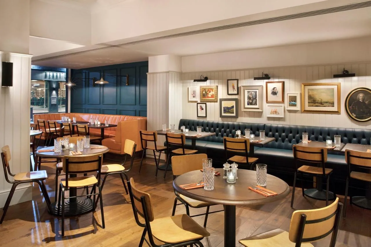 a restaurant with tables and chairs in a room at Leonardo Hotel Cardiff in Cardiff