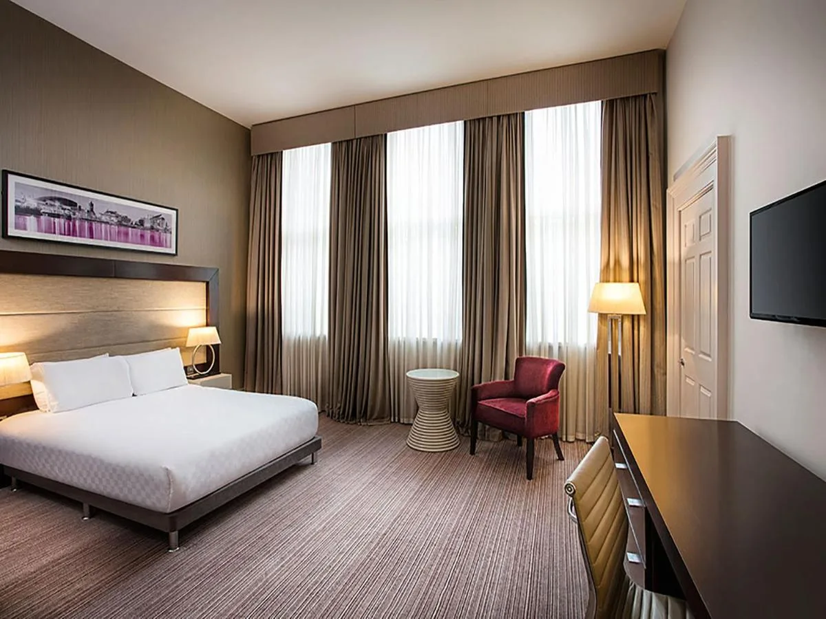 a hotel room with a bed and a red chair at Leonardo Hotel Cardiff in Cardiff