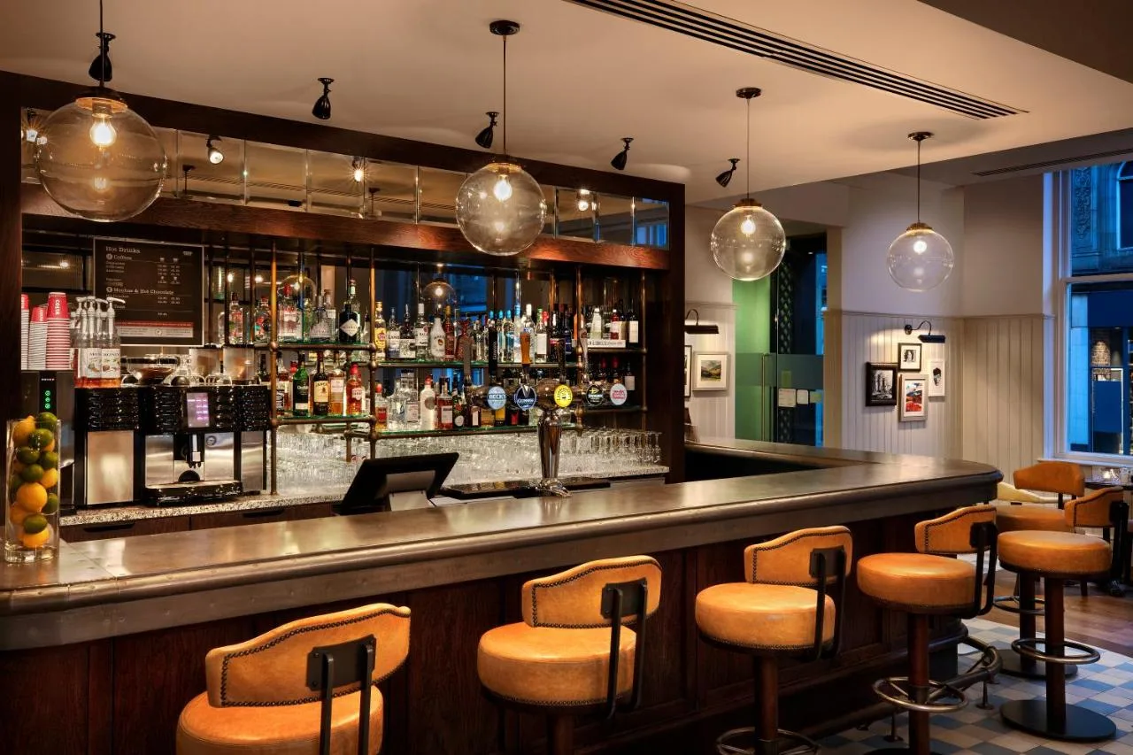 a bar with brown stools in a restaurant at Leonardo Hotel Cardiff in Cardiff
