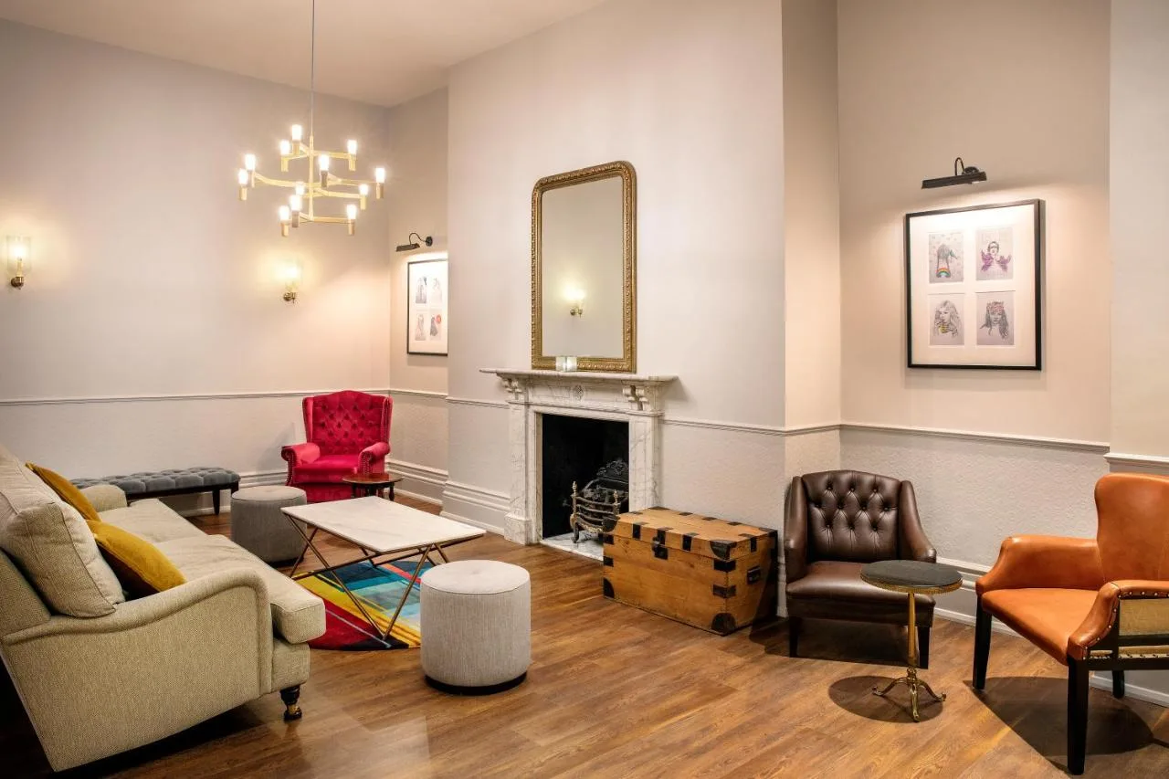 a living room with furniture and a mirror at Leonardo Hotel Cardiff in Cardiff
