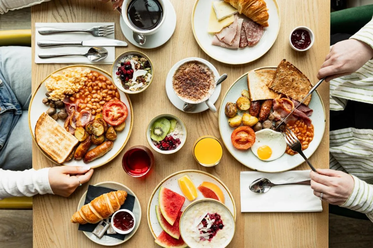 a table with plates of breakfast food on it at Leonardo Hotel Cardiff in Cardiff